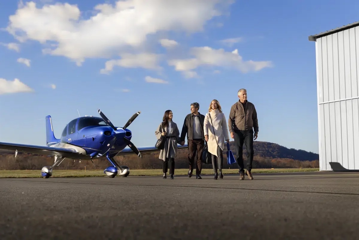 Passengers walking to a Cirrus on the ramp beside the hangar