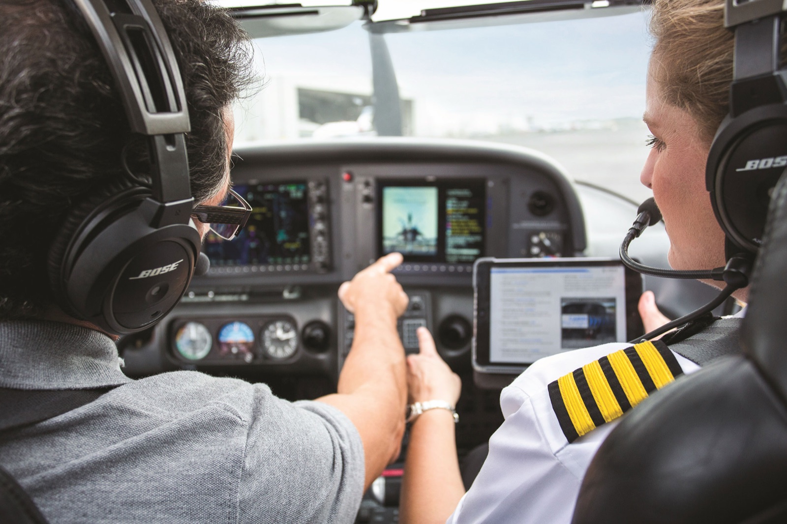 Instructor briefing a uniformed pilot at the panel during commercial training