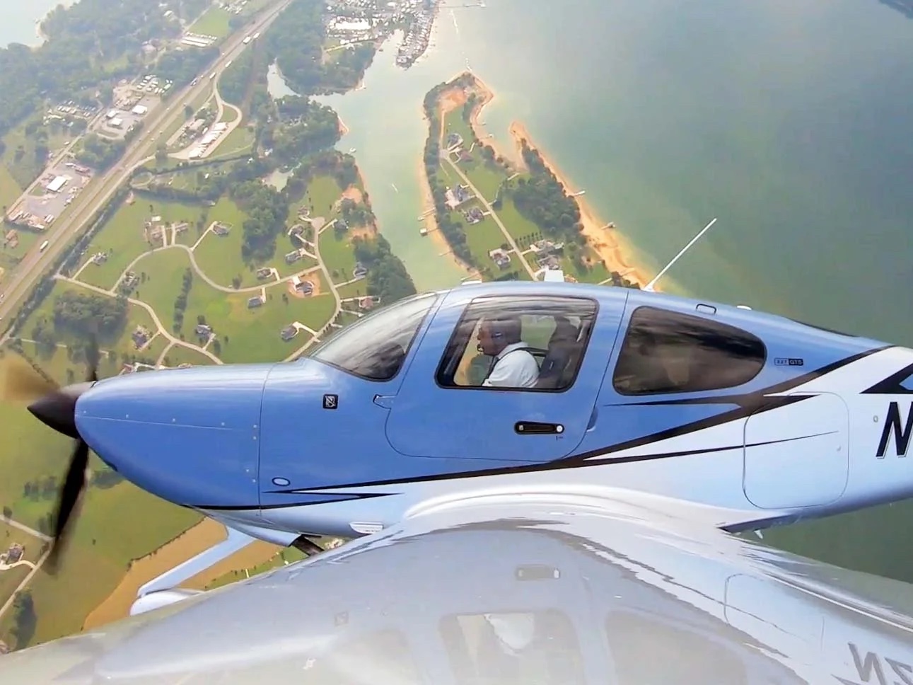 Cirrus in cruise above a coastline, seen from the wing
